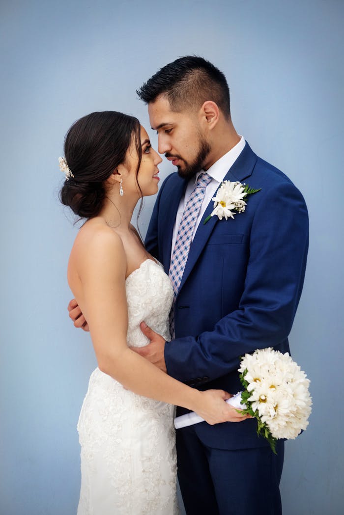 services-05 Bride and groom sharing a tender moment with bouquet against a blue background.
